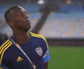 a soccer player is standing on a field wearing a blue and yellow adidas jersey .