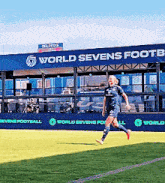 a soccer player is running on the field in front of the world sevens footb