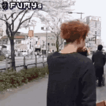 a man with red hair is walking down a street with a futurys logo above him