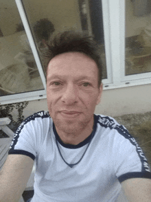 a man taking a selfie wearing a white shirt with a black stripe on the sleeves