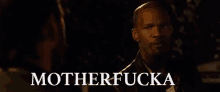 a man is talking to another man in a dark room and the words motherfucka are written on the screen .
