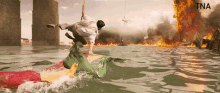 a man in a white shirt is riding a green flag in the water with tna written on the bottom