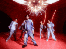 a group of people are dancing in a room with a chandelier in the background