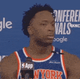 a basketball player in a new york jersey is talking into a microphone .