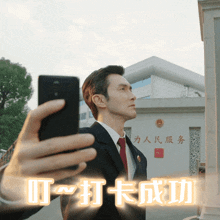 a man in a suit and tie is taking a picture of himself with a cell phone