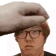 a man wearing glasses and a hat is being touched by a towel .