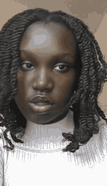 a close up of a woman 's face with braids on her hair