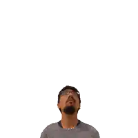 a man with glasses looks up at a green cross above his head