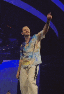 a man in a colorful shirt is dancing in front of a screen that says ' a ' on it