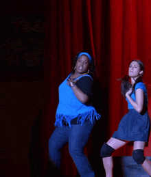 two women are dancing in front of a red curtain that says tea year 1995