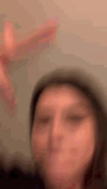 a blurry picture of a woman making a funny face with her hands .