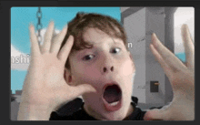 a young boy is making a surprised face with his hands in front of his face .