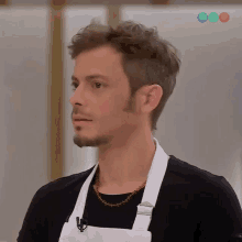 a man wearing a black shirt and a white apron is looking at something