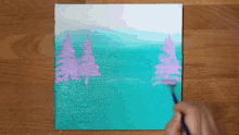 a person is painting a painting of trees on a canvas .