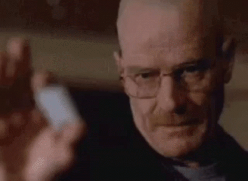a close up of a man wearing glasses holding a pill .