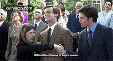 a woman is shaking hands with a man in a suit while a group of people watch .