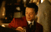 a man wearing a red suit and tie is smiling