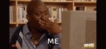 a man is covering his mouth with his hand while looking at a computer screen and says `` me '' .
