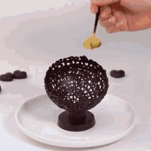 a person is decorating a chocolate bowl with yellow icing