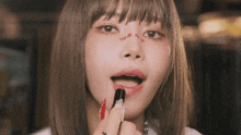a woman applying red lipstick to her lips