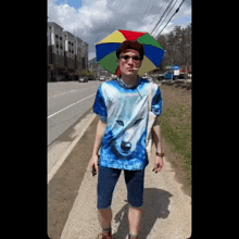 a man wearing a shirt with a wolf on it is walking down the street with an umbrella on his head