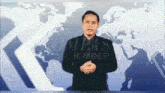 a man in a suit stands in front of a kompas jember map