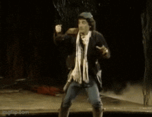 a man with a scarf around his neck is dancing on a stage