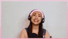 a young woman wearing headphones and a pink headband is singing .