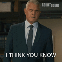 a man in a suit and tie is standing in front of a sign that says countdown