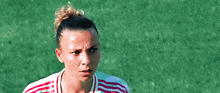 a woman in a soccer uniform is standing on a field .