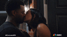 a man and a woman kissing with the nbc logo in the background