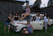 a group of women posing for a picture with a car