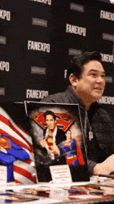 a man sitting at a table with a picture of superman