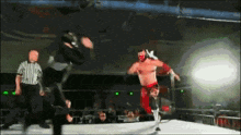 a wrestler in a mask is jumping over another wrestler