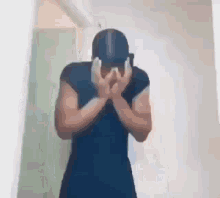 a man is covering his face with his hands while wearing a hat .