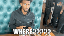 a man in a black nike sweatshirt sits at a table with a plate of food in front of him and the words where ??