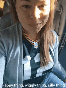 a woman wearing a green bay packers jersey is sitting in a car with the caption happy thing wiggly thing silly thing