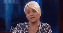 a woman is sitting on a stage with her eyes closed and making a funny face .