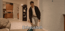 a man is carrying a suitcase in a living room and the word exhaustish is on the bottom