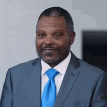 a man in a suit and tie is smiling while looking at the camera .