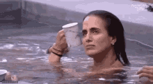a woman is taking a bath in a hot tub while holding a cup of coffee .