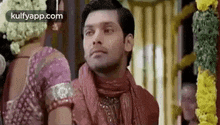 a man in a red scarf is standing next to a woman in a pink shirt .