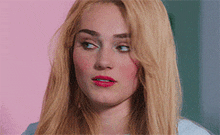 a close up of a woman 's face with blonde hair and red lips .