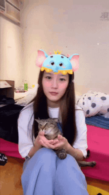 a woman wearing an elephant headband is holding a cat
