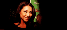 a woman is smiling in the dark in front of a green banner .