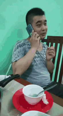 a man sitting at a table talking on a cellphone