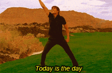 a man in a black shirt is standing in a field with the words today is the day above him