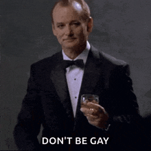 a man in a tuxedo is holding a glass of whiskey .