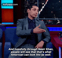 a man in a suit is sitting in a chair and saying and hopefully through nasir khan