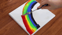 a person painting a rainbow on a canvas with a spatula